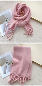 Detail of pink knitted scarf featuring decorative tassels and a minimalist woven label