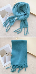 Detail of teal knit scarf showing thick texture, tassels, and HILLDI woven label