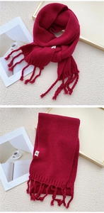 Detail of thick deep red knitted scarf with fringe and soft texture for winter