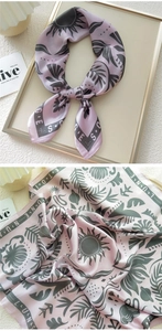Detail of lavender silk scarf with green sun and palm patterns on a satin texture
