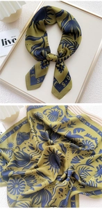 Detail of silk scarf with olive green leaves and navy sunflower pattern on smooth fabric