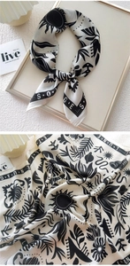 Detail of cream silk scarf with black botanical patterns and elegant script printing