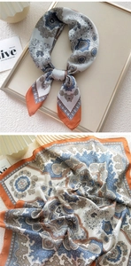 Close-up of vintage paisley silk scarf with elegant orange contrast border and soft texture