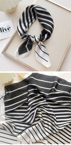 Close-up of black and white striped satin scarf with elegant draped texture and sheen