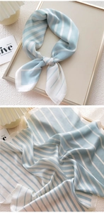 Detail view of light blue and white striped silk scarf with elegant drape and smooth texture