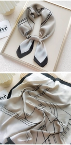 Close-up of a high-quality satin square scarf with minimalist black abstract lines and fine trim