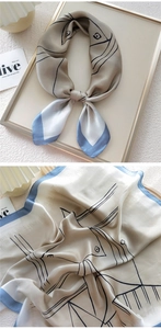 Macro view of silk scarf with minimalist black fish pattern on beige and blue fabric