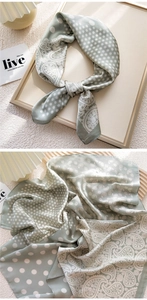 Close-up of sage green silk scarf with white polka dots and paisley patterns