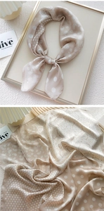 Detail of champagne paisley and polka dot silk scarf with elegant satin finish texture