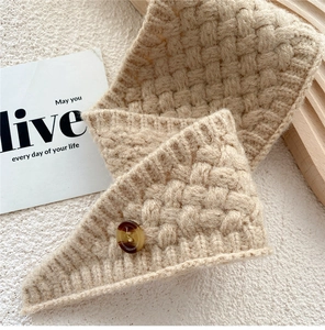 Detail of camel knit scarf featuring chunky textured weave and amber button closure