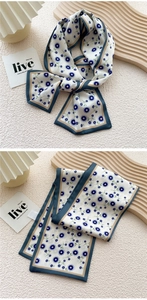 Detailed shot of floral narrow silk scarf with elegant blue pattern and contrast borders