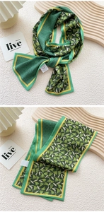 Detailed view of green and yellow silk scarf with ginkgo leaves on a wooden tray