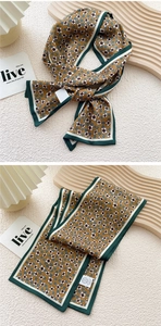 Close-up of yellow floral silk scarf with dark green border and fabric care label