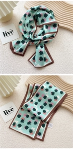 Detail of mint green floral skinny silk scarf with elegant pattern and brown hem edge