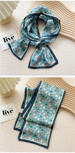 Detail of light blue floral skinny scarf with contrast borders on a textured background