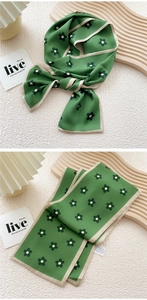 Detailed view of dark green floral silk skinny scarf with a beige border and wash label
