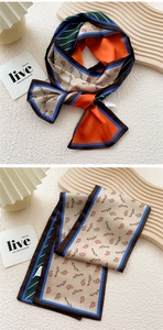 Detail view of a multi-color silk-like scarf with floral prints and orange accents