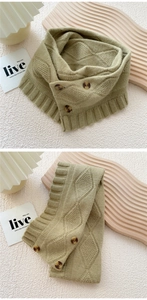 Close-up of olive green knit scarf with textured diamond pattern and three brown buttons