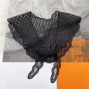 Detail of black lace neck scarf featuring intricate hollow embroidery and bow tie design