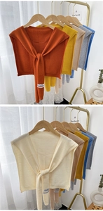 Macro detail of various soft knit shawl wraps hanging on a stylish golden rack