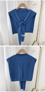 Close-up of blue knitted shawl with knotted front tie and premium brand woven label detail