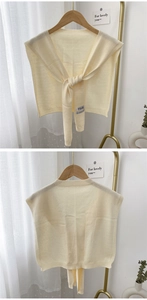 Detail of cream knit shawl with textured ribbed edges and elegant tie-front strings