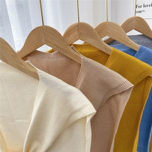 Solid color knit shawl wraps for women shown in multiple soft colors on wooden hangers