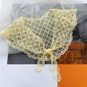 Detailed view of light yellow lace neckerchief with floral mesh pattern and wavy edges