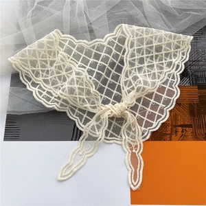 Detail of off-white lace neck scarf with intricate mesh embroidery and bow tie