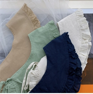 Detailed view of ruffled fake collars in navy, sage, khaki, and cream cotton-linen fabric