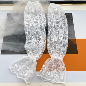 Close-up of white floral lace arm sleeves with elegant ruffles and embroidery detail