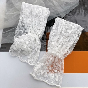 Close-up of white floral lace arm sleeves with intricate leaf and flower embroidery
