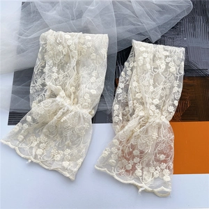 Detail of floral lace sleeve covers with intricate embroidery and scalloped edges