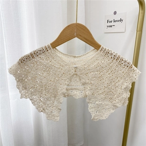 Floral crochet lace shawl collar with pearl buckle on wooden hanger in cozy setting