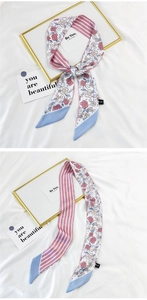 Detail of silk floral scarf showing pink rose patterns and striped reverse on white cloth