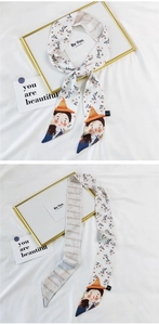 Detail of floral silk twilly with cartoon girl illustration and brand logo lettering