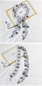 Detail of silk scarf with purple floral and beetle prints on white background