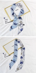 Close-up of a double-sided silk hair ribbon twilly with bird silhouettes and floral patterns