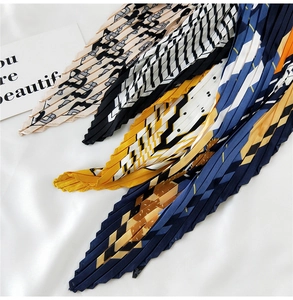 Detail of pleated silk scarves featuring letter prints and geometric patterns on satin