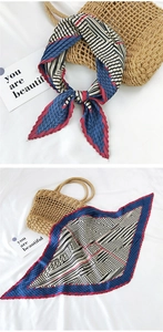 Detail of pleated square silk scarf with geometric color-blocking on white background