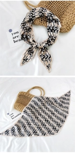 Detail view of beige pleated silk scarf with black abstract geometric print patterns