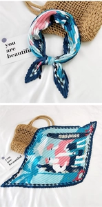 Detail of pleated silk scarf with colorful surfing print and zigzag edges on white fabric