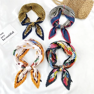 Pleated square silk scarves featuring various geometric patterns in a 2x2 flat lay display