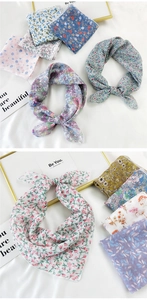 Detail of assorted floral cotton linen scarves tied in bows on a white background