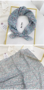 Close-up of floral linen scarf fabric with light green background and small blossoms