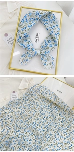 Close-up detail of blue floral cotton linen scarf tied in a bow with pattern view