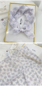 Detail of floral linen-cotton small square scarf tied neatly on a gold frame