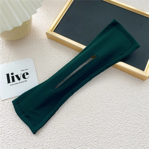 Detail view of a dark green fabric deft bun hair maker tool on a minimalist desk surface