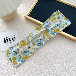 Close-up of floral fabric hair bun maker tool with metal wire on white textured table