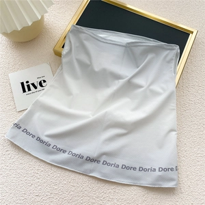 Détail de la jupe en maille gris clair avec motifs Dore Doria répétés sur le bord inférieur